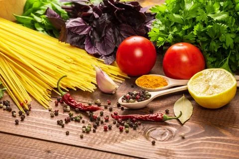 Raw pasta, vegetables, basil and spices on the wood table 写真素材