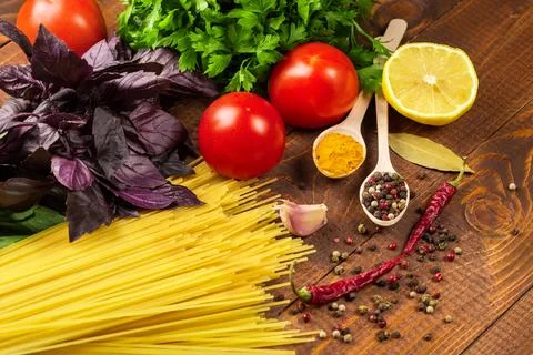 Raw pasta, vegetables, basil and spices on the wood table Stock Photos