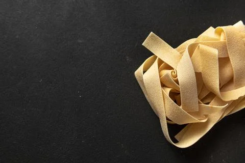 Raw paste pappardelle on a dark background. Stock Photos