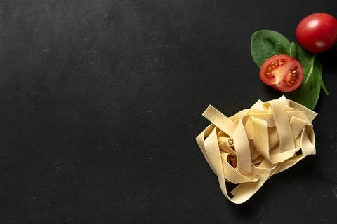 Raw paste pappardelle on a dark background. Stock Photos