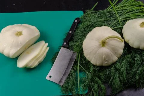 Raw Pattypan squashes, a kitchen hatchet, a bunch of fresh dills, and a green Stock Photos