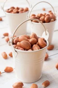 Raw peanuts or arachis in white bucket on wooden board, healthy food Stock Photos