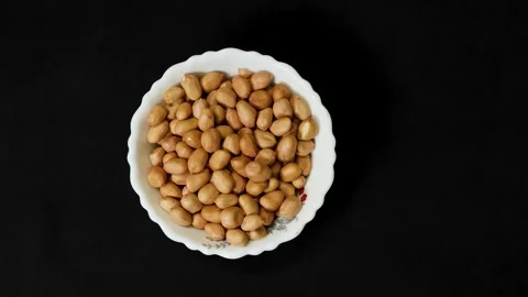 Raw peanuts in white bowl isolated on black background healthy snack concept Stock Footage 336646177