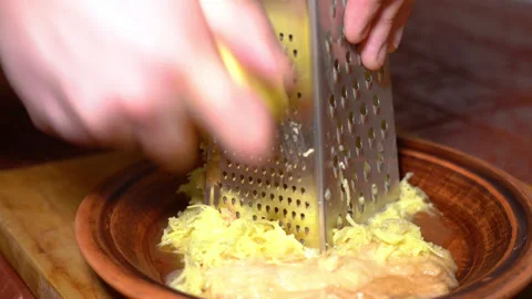 Raw peeled potato grated on the kitchen grater into the plate Stock Footage 247845257