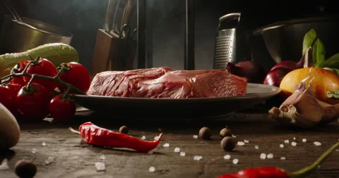 A raw piece of meat on preparation table of kitchen. Steak and various vegetable Stock Footage 144498650
