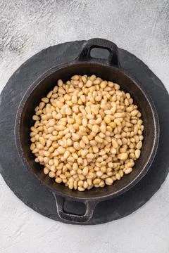 Raw pine nuts arranged in a small cast iron dish on a slate plate over a li.. Stock Photos