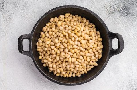 Raw pine nuts arranged in a small cast iron dish on a slate plate over a li.. Stock Photos