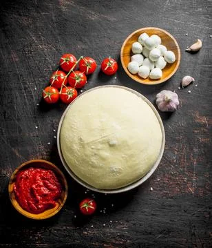 Raw pizza. Dough with tomato paste, mozzarella and cherry tomatoes. Stock Photos