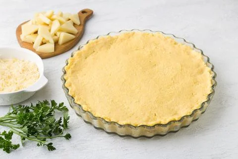 Raw polenta in a baking dish, two types of cheese and parsley on a light gr.. Stock Photos