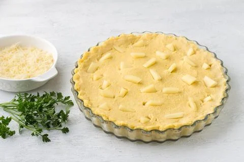Raw polenta in a baking dish, two types of cheese and parsley on a light gr.. Stock Photos