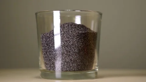 Raw poppy seeds in transparent glass with white reflection Stockbeeldmateriaal 75241553