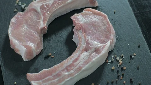 Raw pork chops with bone. Rosemary falls on raw meat. 動画素材 106471047