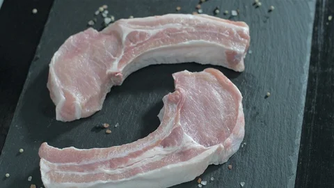 Raw pork chops with bone. Rosemary falls on raw meat. Video stock 106471131