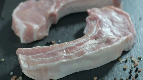 Raw pork chops with bone. Rosemary falls on raw meat. Stock Footage 106471157
