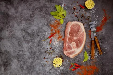 Raw pork chops with spices on dark background. Stock Photos