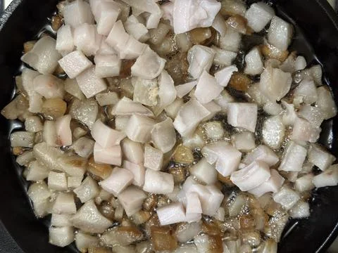 Raw pork fat rendering in pan Stock Photos