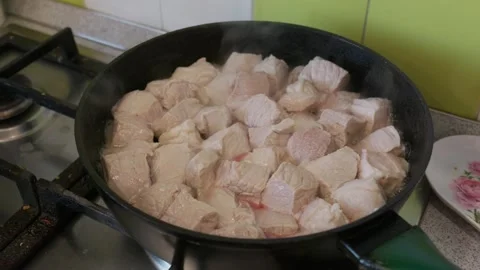 Raw Pork Meat Cubes Stewing in Black Frying Pan on Kitchen Stove Stock Footage 341982550