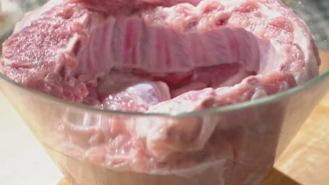 Raw pork meat turning in a crystal bowl Stock Footage 192534814