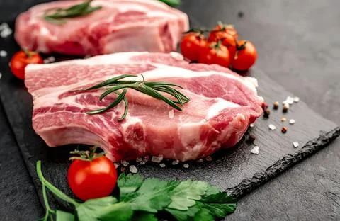 Raw pork ribs with cherry tomatoes and herbs on slate 写真素材