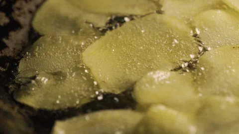 Raw potato chips getting fried on a pan full of boiling oil. Macro shot. Slowmo Stock Footage 142280610