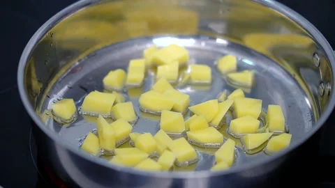 Raw potato sliced in cubes is fried in metal frying pan made of stainless steel Stockbeeldmateriaal 260740438