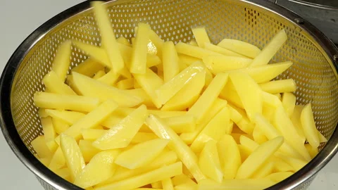 Raw Potato Strips Falling into Metal Colander for Draining Stock Footage 343941410
