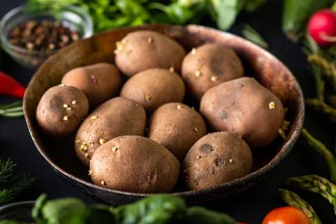 Raw potato tubers. Various vegetables around. Vegetarian food. Stock Photos