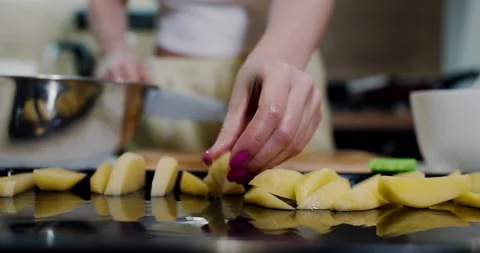 Raw potatoes, cut on a baking tray on the kitchen table. Slow motion. Stock Footage 148554364