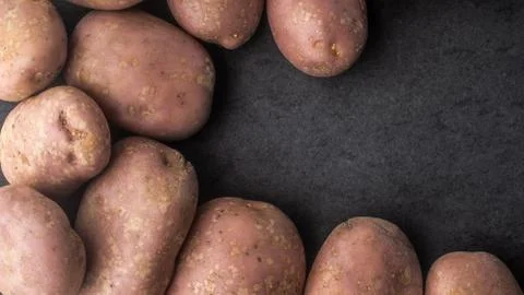 Raw potatoes on the dark stone table horizontal Stock Photos