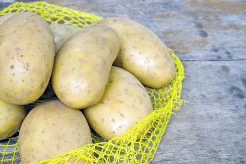 Raw potatoes on the net for cooking Stock Photos