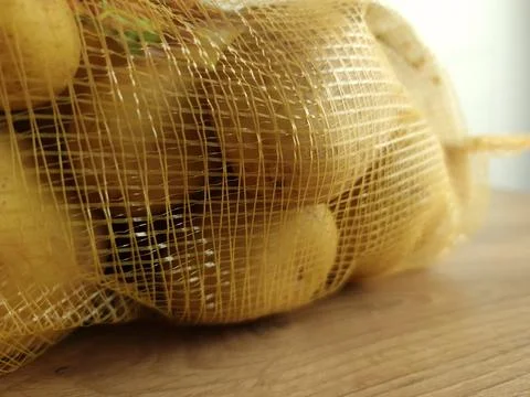 Raw potatoes in net pack Stock Photos