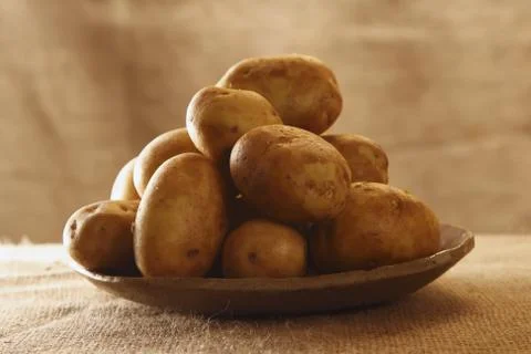 Raw potatoes on plate with burlap rustic background Stock Photos