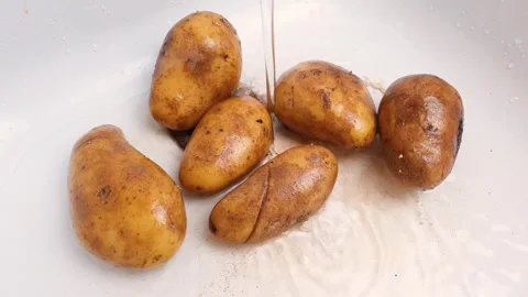 Raw potatoes under running water in the kitchen sink, sink. Wash potatoes before Stock Footage 313352086