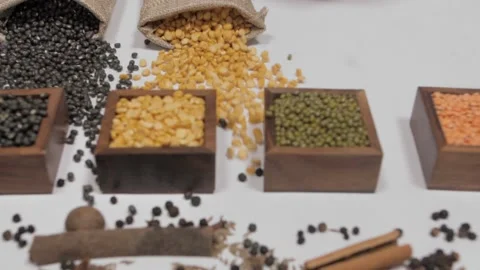 Raw pulses falling from gunny bag in front of wooden containers with Dal/lentils Video stock 145248558