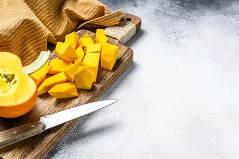 Raw pumpkin cubes on a cutting Board. White background. Top view. Copy space Stock Photos