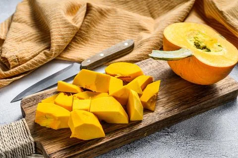 Raw pumpkin cubes on a cutting Board. White background. Top view Stock Photos