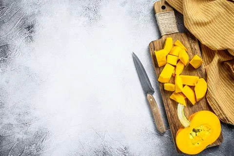 Raw pumpkin cubes on a cutting Board. White background. Top view. Copy space Stock Photos