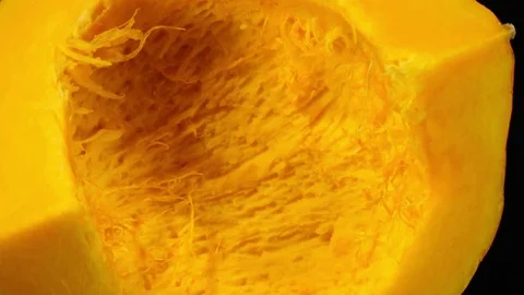 Raw pumpkin quarter without seeds rotates over black background. 4K Vidéo 74060589
