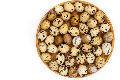 Raw quail eggs on a white background on a plate, top view, healthy eating con Stock Photos