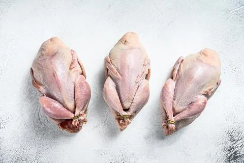 Raw quails on a kitchen table. White background. Top view Stock Photos