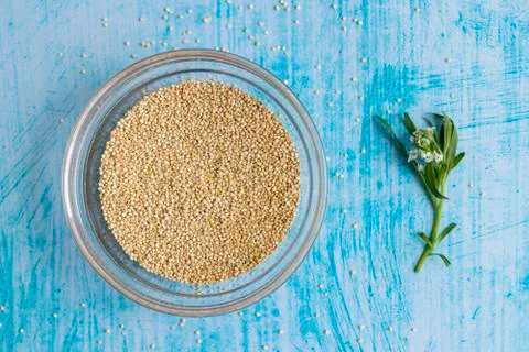 Raw quinoa grains inside transparent bowl, on blue table Stock Photos