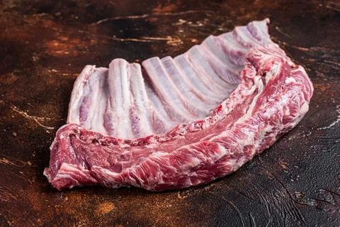 Raw rack of mutton lamb ribs on butcher board. Dark background. Top view Stock Photos