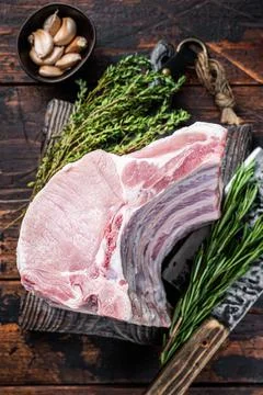Raw rack of pork loin chops with ribs on a butcher board with meat cleaver. Dark Stock Photos