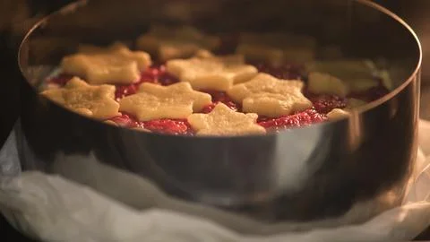 Raw raspberry pie with star-shaped shortcrust pastry on top baking in metal c Foto stock