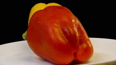 Raw red and yellow bell peppers rotate on a whait plate Stock Footage 149470993