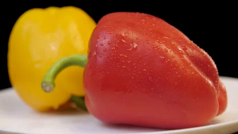 Raw red and yellow bell peppers rotate on a whait plate Stock Footage 149805518