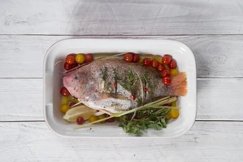 Raw red tilapia fish cooked with herbs, spices, paprika and tomatoes, lemon, Stock Photos