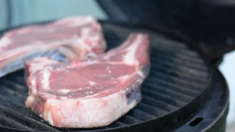 Raw rib steak on the grates of a heated grill Видео 242242480