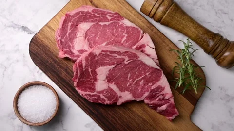 Raw ribeye steak beef on white marble background Stock Footage 260963987
