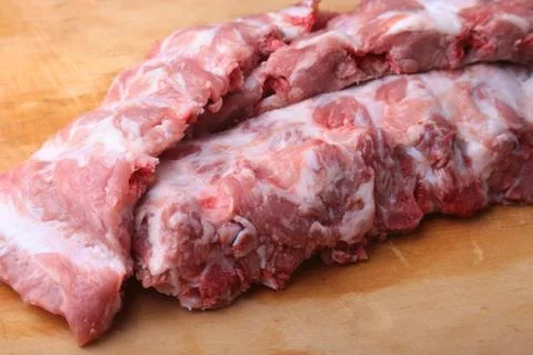 Raw Ribs on a rustic cutting board with salt, pepper . copy space. Stock Photos